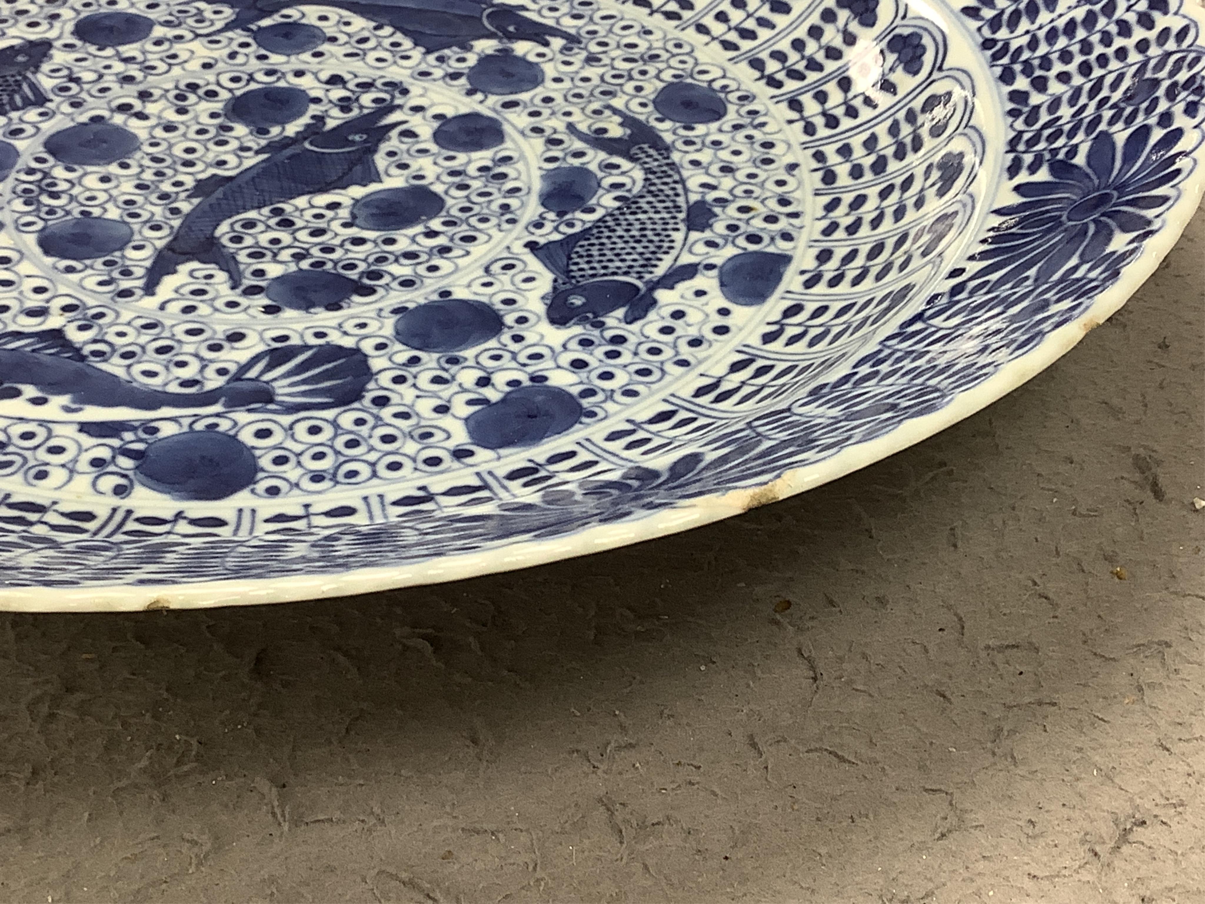 A Chinese blue and white 'fish' dish, Kangxi mark but c.1900, 33cm diameter. Condition - slight chipping to rim